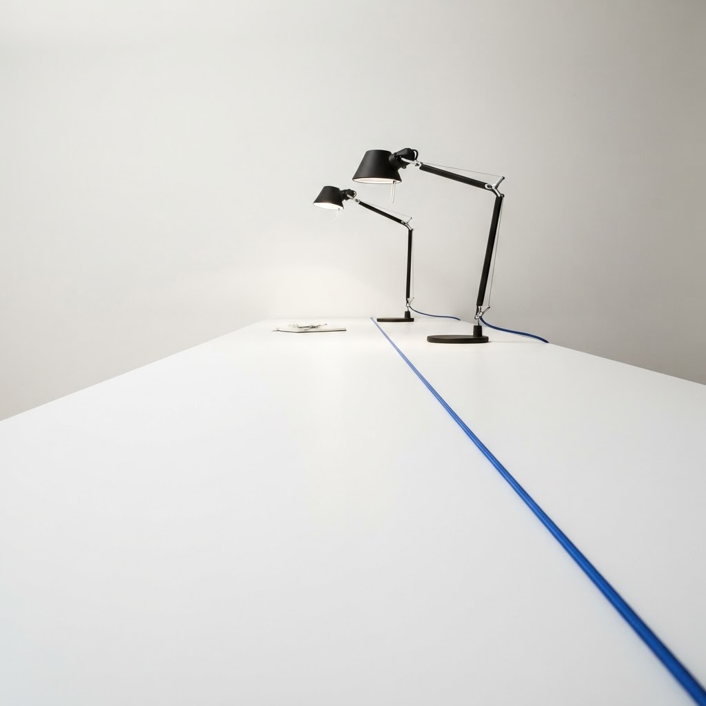 Two desk lamps on a white surface with a blue cable